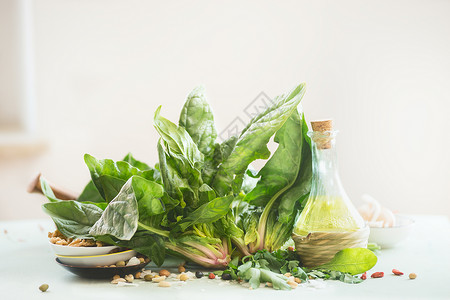 新鲜的有机菠菜带橄榄油瓶放厨房的桌子上,背景很轻健康的烹饪理念背景