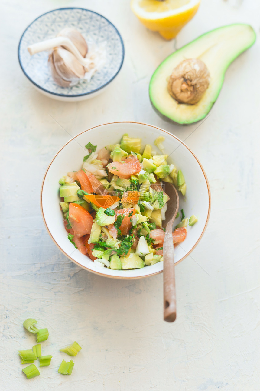 美味的新鲜鳄梨番茄沙拉白色厨房桌子背景,顶部视图健康的食物素食午餐或小吃图片