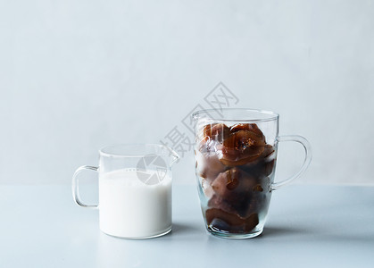 咖啡冰块玻璃杯小罐与奶油或纯素牛奶灰色桌子墙壁背景清爽的夏季饮料,制作配料图片