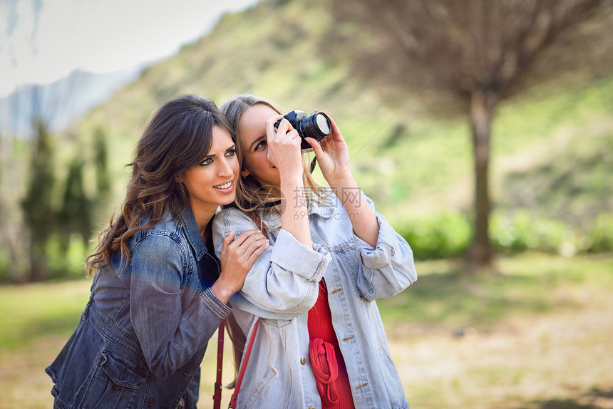 两名年轻的旅游妇女城市公园用类似的反射相机拍照旅行者的图片