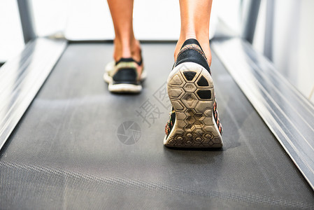 女人鞋肌肉发达的脚穿着运动鞋健身房的跑步机上跑步背景