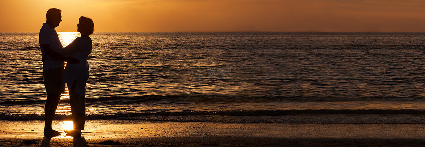 快乐的老年男女夫妇日落时拥抱拥抱个荒芜的热带海滩全景网络横幅上图片