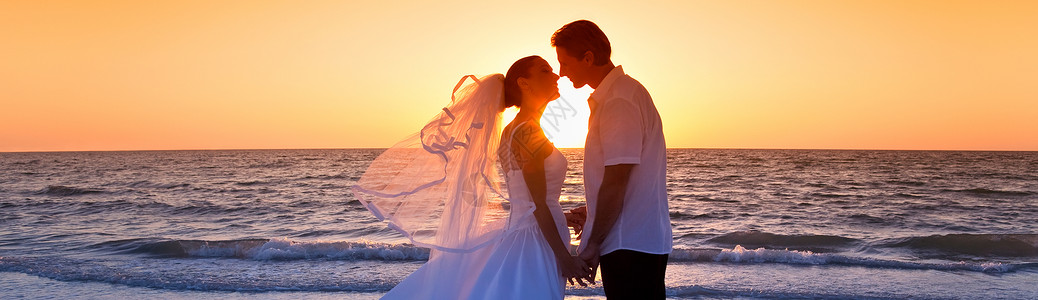 已婚夫妇,新娘新郎,日落时亲吻个美丽的热带海滩婚礼全景图片