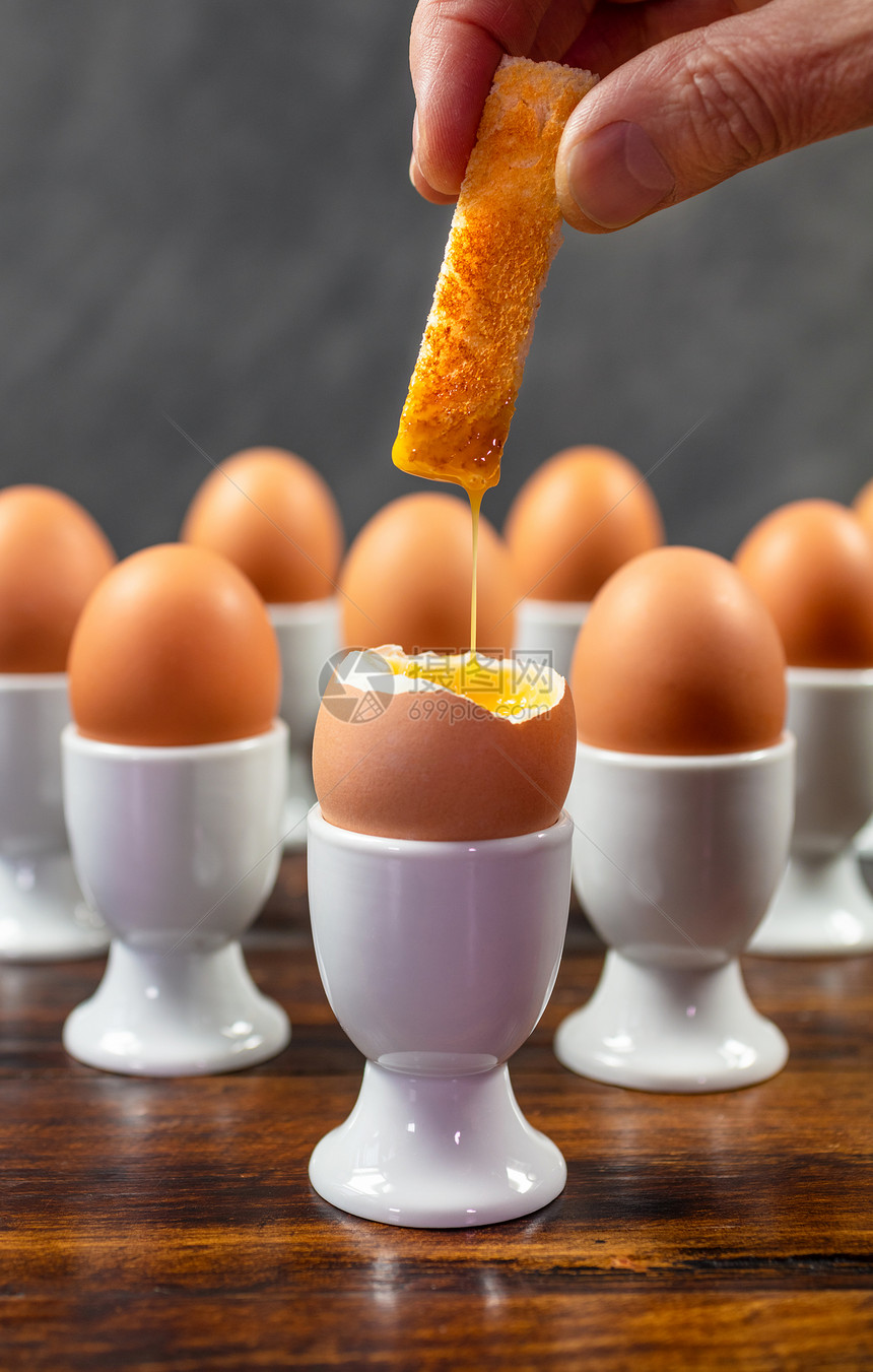 人蘸吐司士兵个煮鸡蛋的鸡蛋白蛋杯个木桌上图片