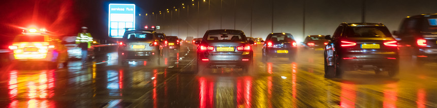 全景运动模糊的照片,夜间雨中与汽车英国高速公路上的交通图片
