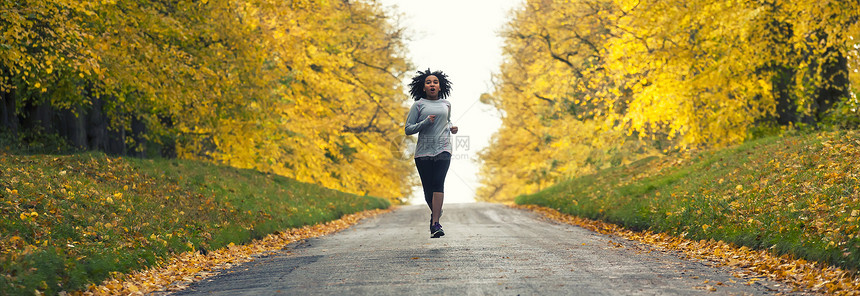 全景美丽的混合种族非裔美国年轻女子青少年健身跑步慢跑秋天秋天的树图片