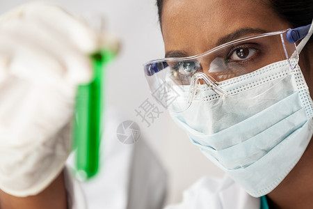 亚洲女医学或科学研究员或医生实验室或实验室里看绿色溶液的试管图片