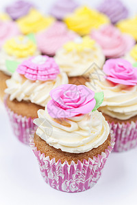 玫瑰线禁止进入杯子蛋糕与糖霜或霜,粉红色,紫色,黄色奶油与绿叶,玫瑰花卉装饰拍摄白色背景背景