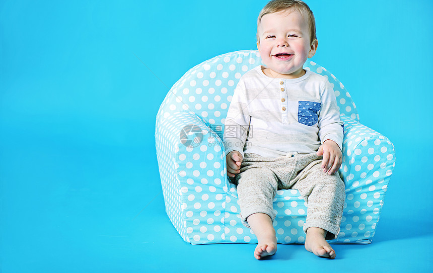 小男孩坐有斑点的玩具扶手椅上图片