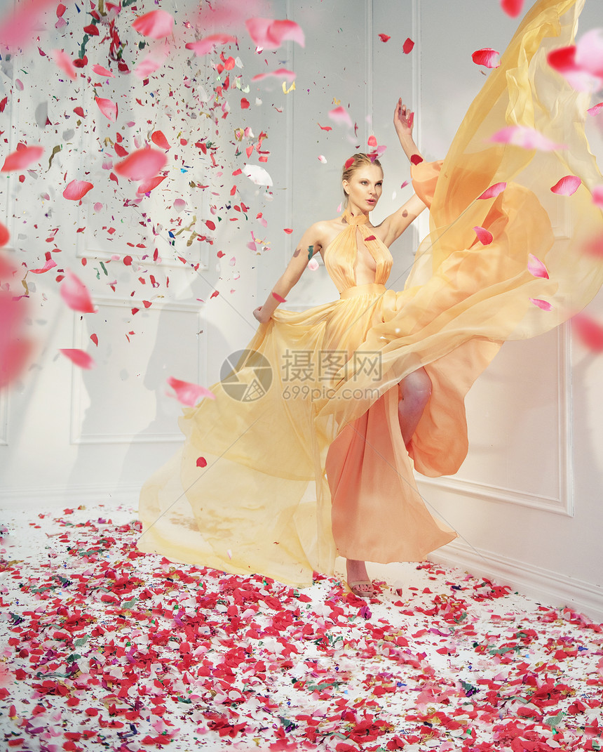 美丽的年轻女人玫瑰花瓣的雨中图片