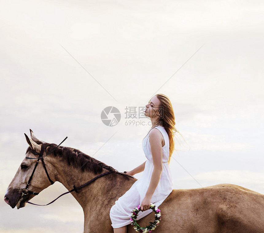 疲惫的金发女人骑着匹棕色的马休息图片