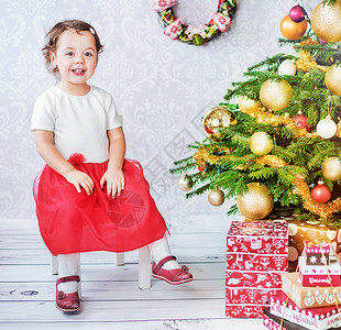 可爱的小孩子坐圣诞树旁边图片