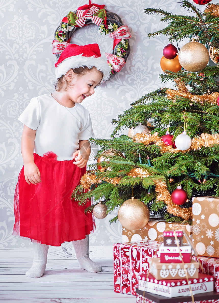 圣诞树旁边个满意的小女儿的肖像图片
