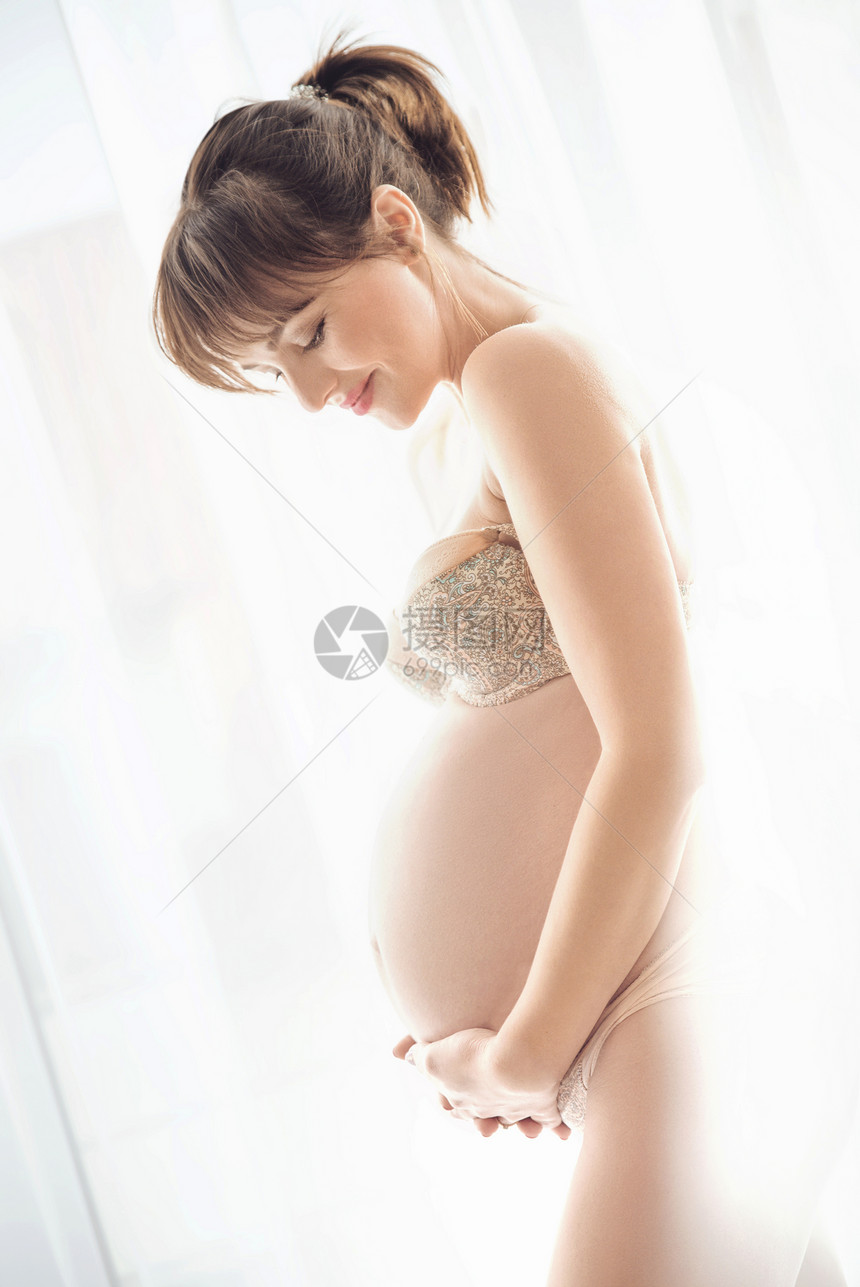 位迷人的怀孕母亲抚摸着肚子的肖像图片