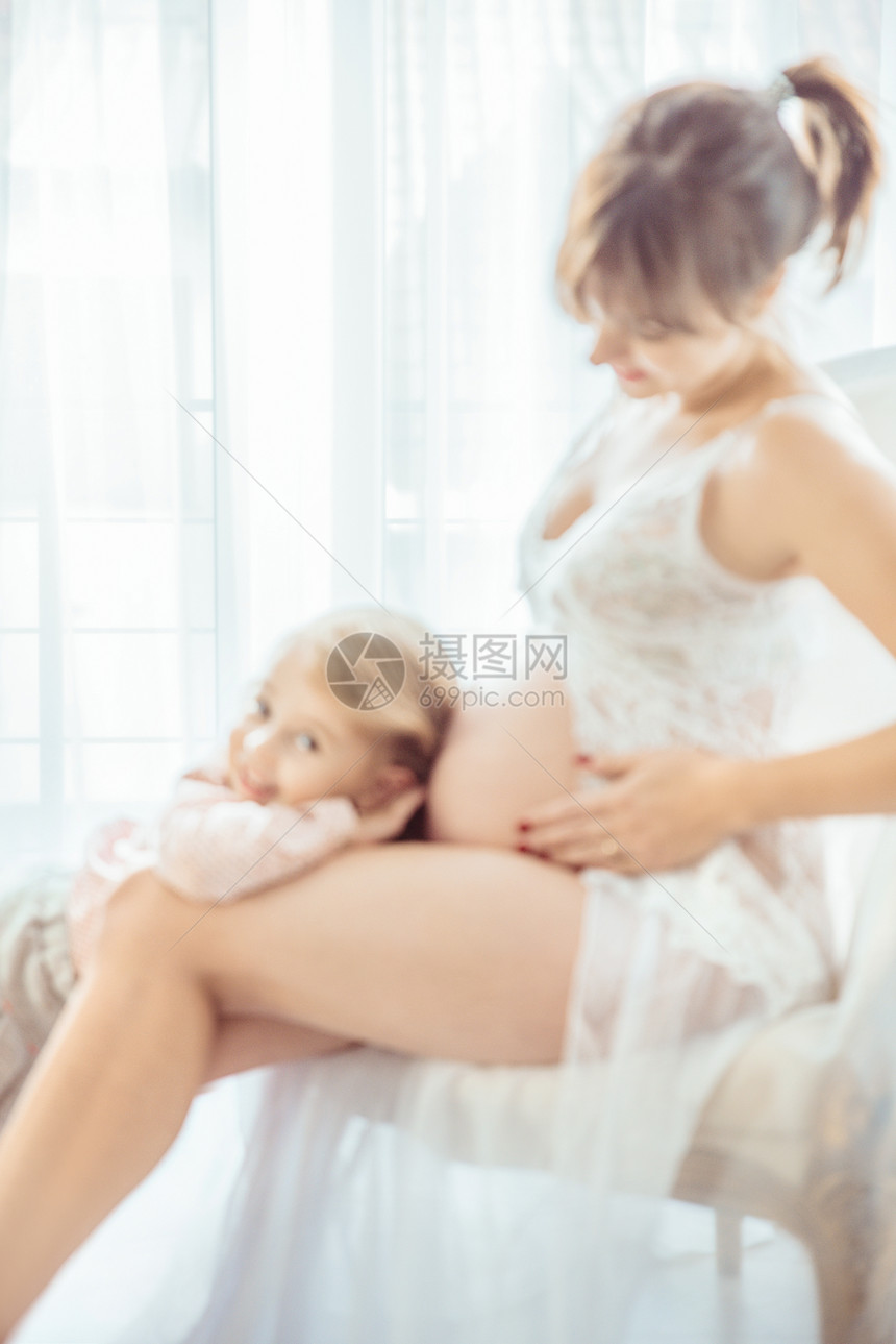 迷人的小女儿抚摸着怀孕的母亲的肚子图片