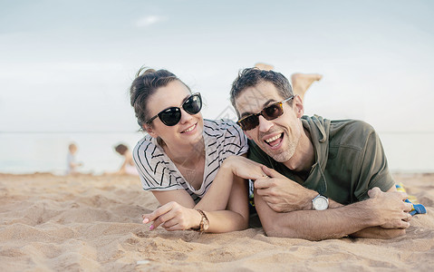 欢快轻松的夫妇躺温暖的沙滩上的肖像图片