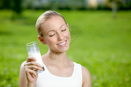 梦想中的金发女郎坐公园的草地上喝牛奶图片