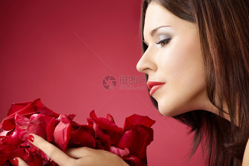 女孩的轮廓闻着玫瑰花瓣,孤立红色的背景上图片