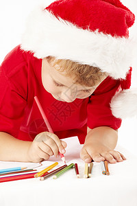 戴着圣诞老人帽子的小男孩床单上画画图片