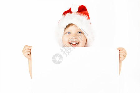 穿着圣诞老人衣服的笑着的小男孩展示了空白的床单,图片