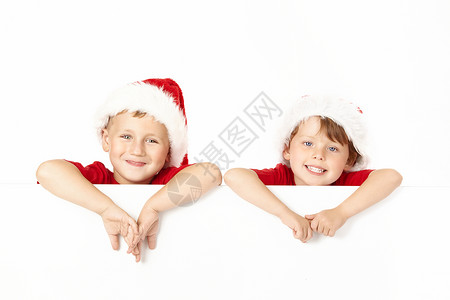 两个戴着圣诞老人帽子的小男孩靠空白横幅上图片