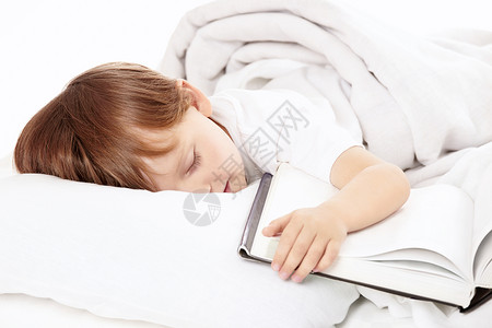 小男孩睡床上拥抱着书,图片