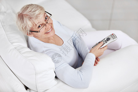 位老妇人躺沙发上,电视上有遥控器图片