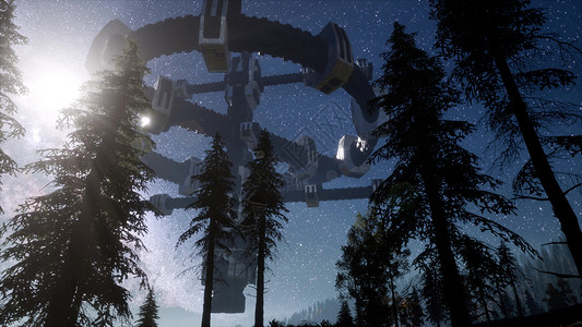 UFO夜间用光束盘旋森林上空高清图片