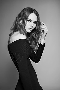 时尚工作室的年轻女子肖像黑色连衣裙卷亮的女士黑白照片背景图片