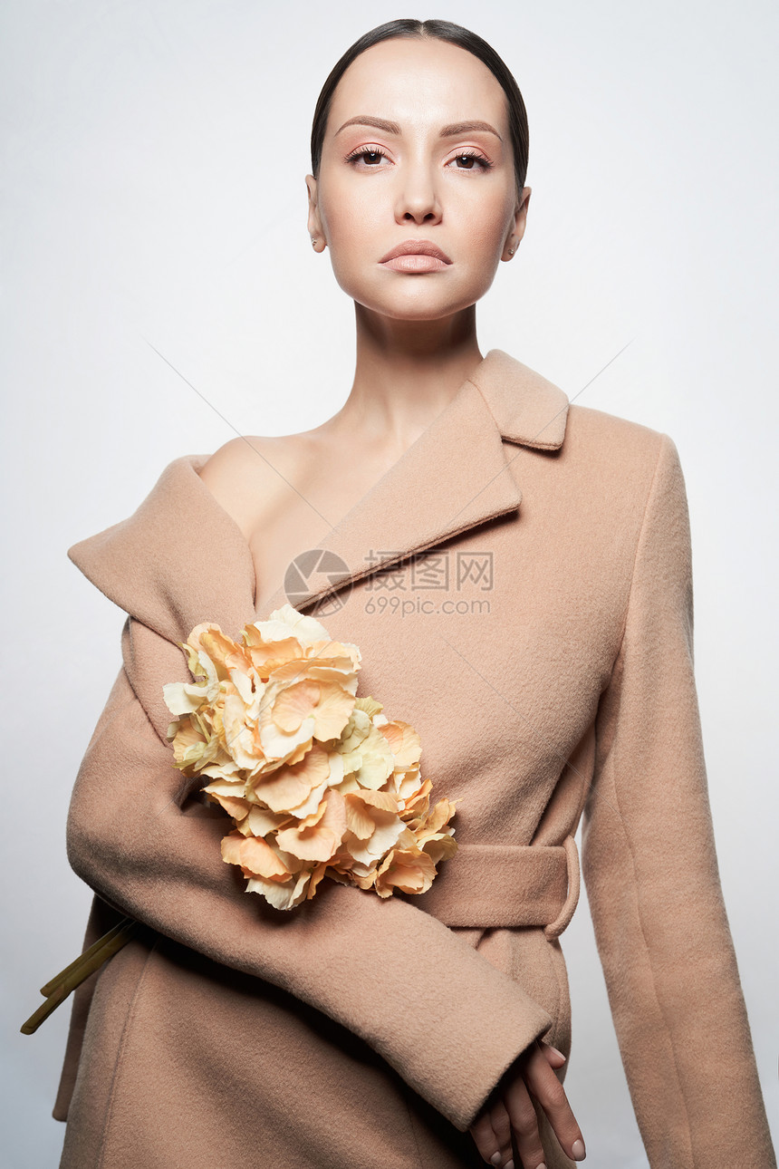 时尚工作室照片,年轻美丽的女士穿着称的米色外套,白色背景上有米色绣球花时尚看书温暖的秋天温暖的春天图片
