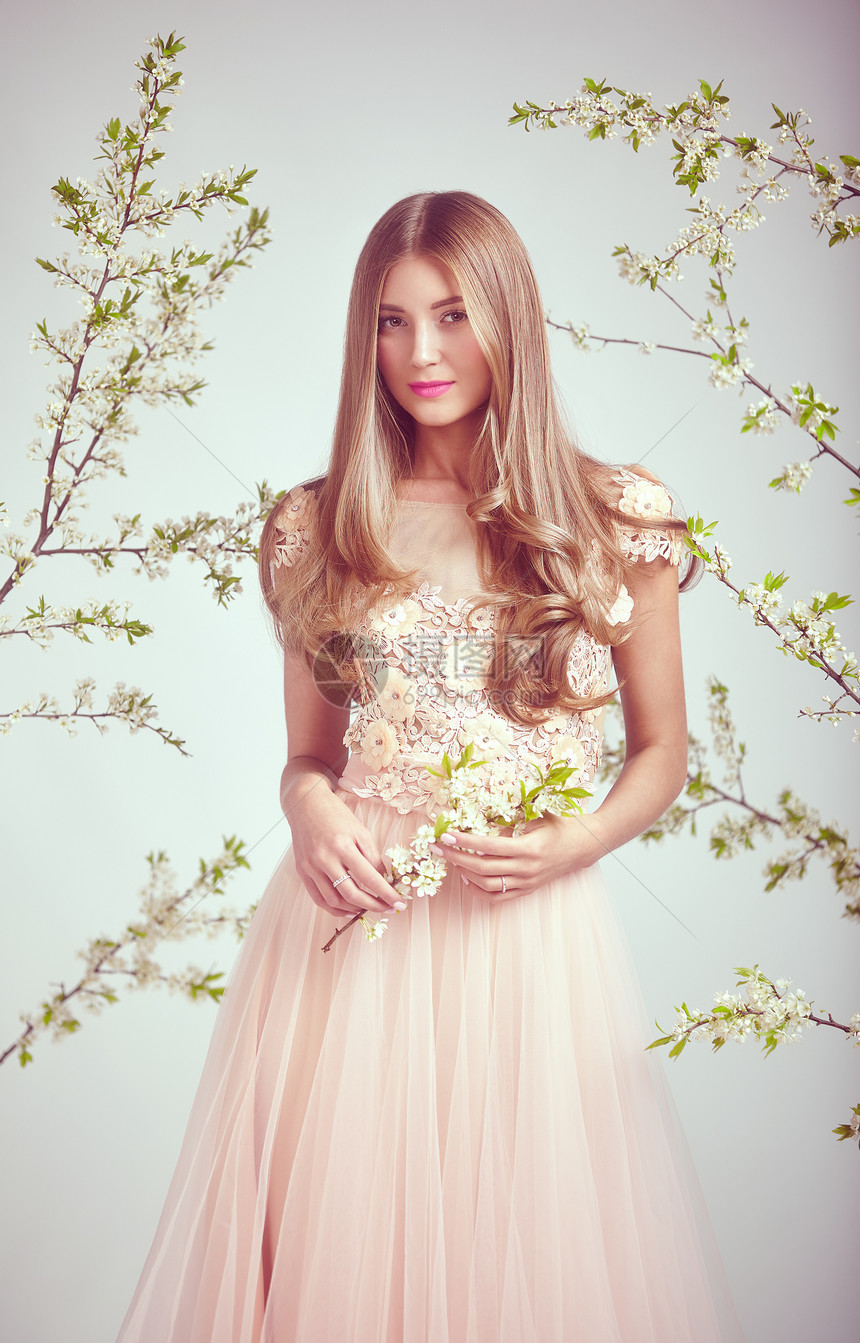 穿着蕾丝婚纱的漂亮女人美丽的女士,健康美丽的头发模型摆棵盛开的苹果树的背景上春天的照片图片