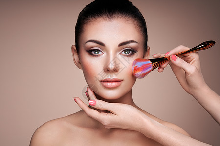 美丽的女人用刷子涂肤色漂亮的女人脸完美的妆容护肤基金会刷化妆师图片