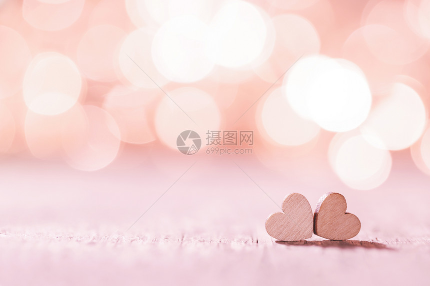 两颗手工制作的粉红色木心明亮的灯光背景下波基背景上的粉红色心脏图片