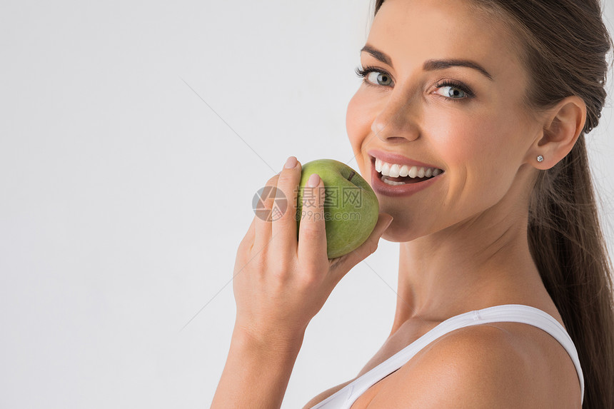 有健康牙齿的年轻女人微笑着咬着绿色的苹果女人咬绿苹果图片