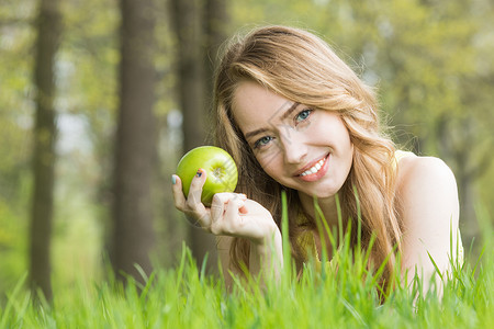 金亮的女孩躺春天公园的草地上,微笑着着新鲜的绿色苹果有绿苹果的女人图片