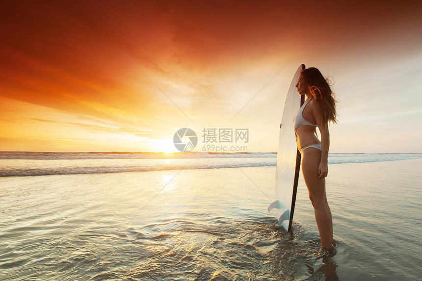 日落时海滩上美丽的冲浪女子日落时海滩上的冲浪女子图片