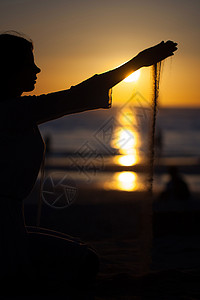 个年轻女孩的剪影,日落时,海滩上向黄色的天空大海倒沙女孩日落时倒沙图片
