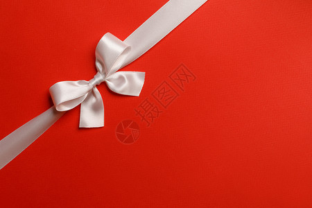 包角装饰素材闪亮的白色缎带红色背景的蝴蝶结节日礼物的闪亮的白色丝带蝴蝶结红色背景