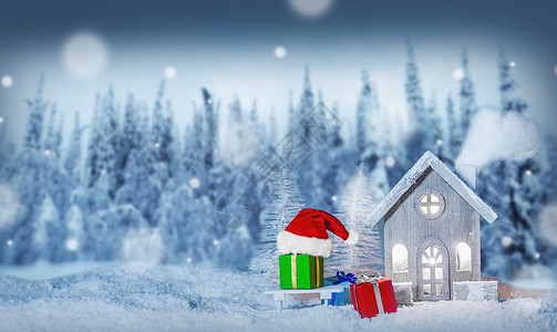 圣诞卡,舒适的小装饰房子,礼物圣诞老人的帽子,雪橇上的雪,童话冬天的冷杉森林背景下雪新年明信片文本圣背景图片