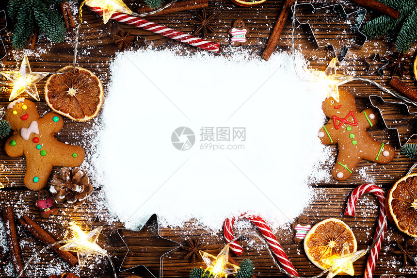 圣诞食品框架姜饼饼干,香料装饰木制背景与雪上圣诞食品框架图片
