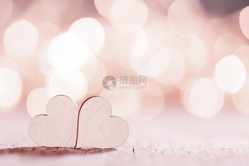 两颗木制的心粉红色发光的Bokeh心脏背景为情人节两颗心闪闪发光图片