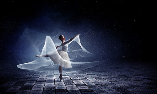 优雅的女舞者穿着白色的连衣裙,黑暗的背景下跳芭蕾的舞者背景图片