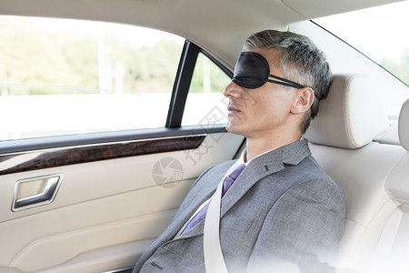 成熟的商人车里戴着眼罩打盹图片