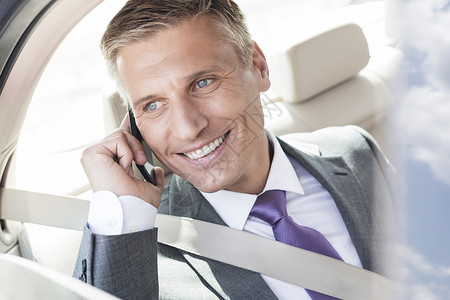 微笑成熟的高管汽车智能手机上交谈图片