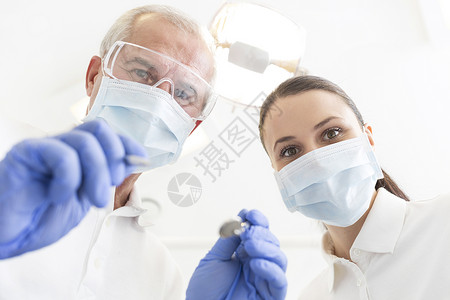 牙科诊所戴口罩的男女牙医的低角度肖像图片