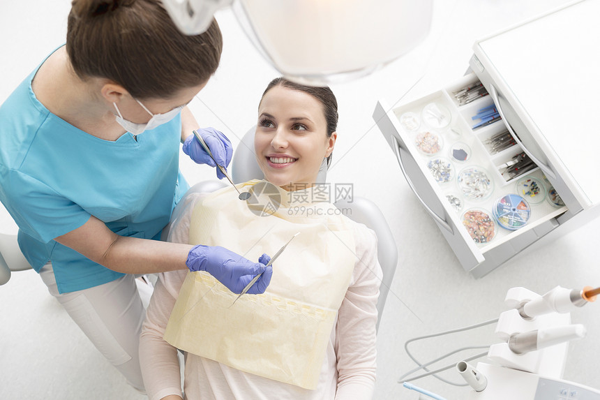 病人治疗过程中用设备看牙医的高角度视图图片