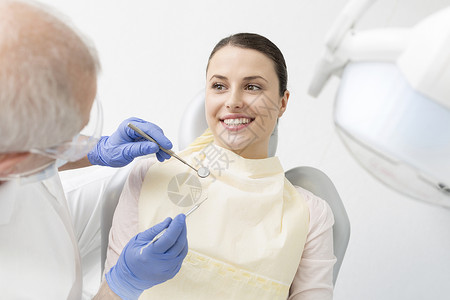 资深牙医检查年轻病人的牙科设备诊所图片