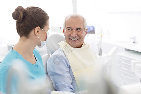 女牙医牙科诊所与微笑的老年病人交谈图片