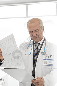 高级医生诊所的剪贴板上阅读医疗报告图片