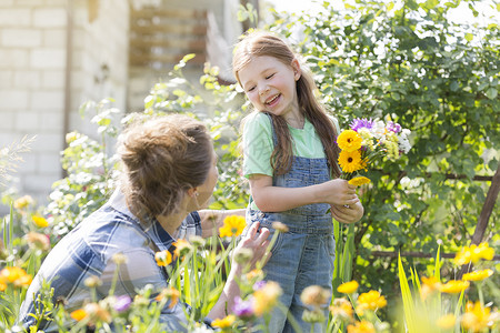 微笑的女孩带着鲜花看着农场的母亲图片